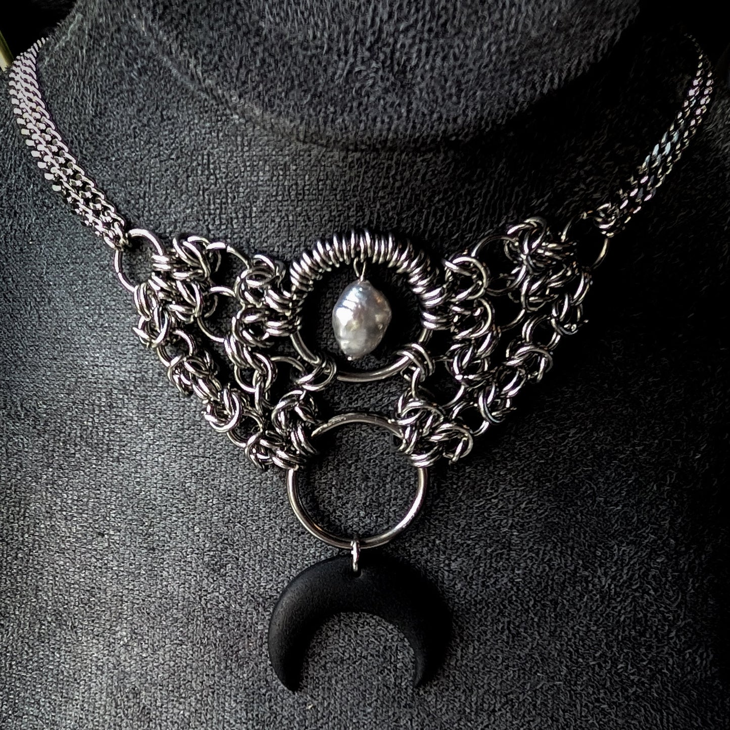 Stainless steel chainmaille necklace with a crescent moon pendant on a dark background