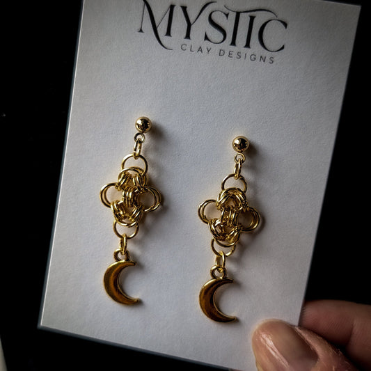 Gold chain earrings with moon charms on a Mystic Clay Designs card.