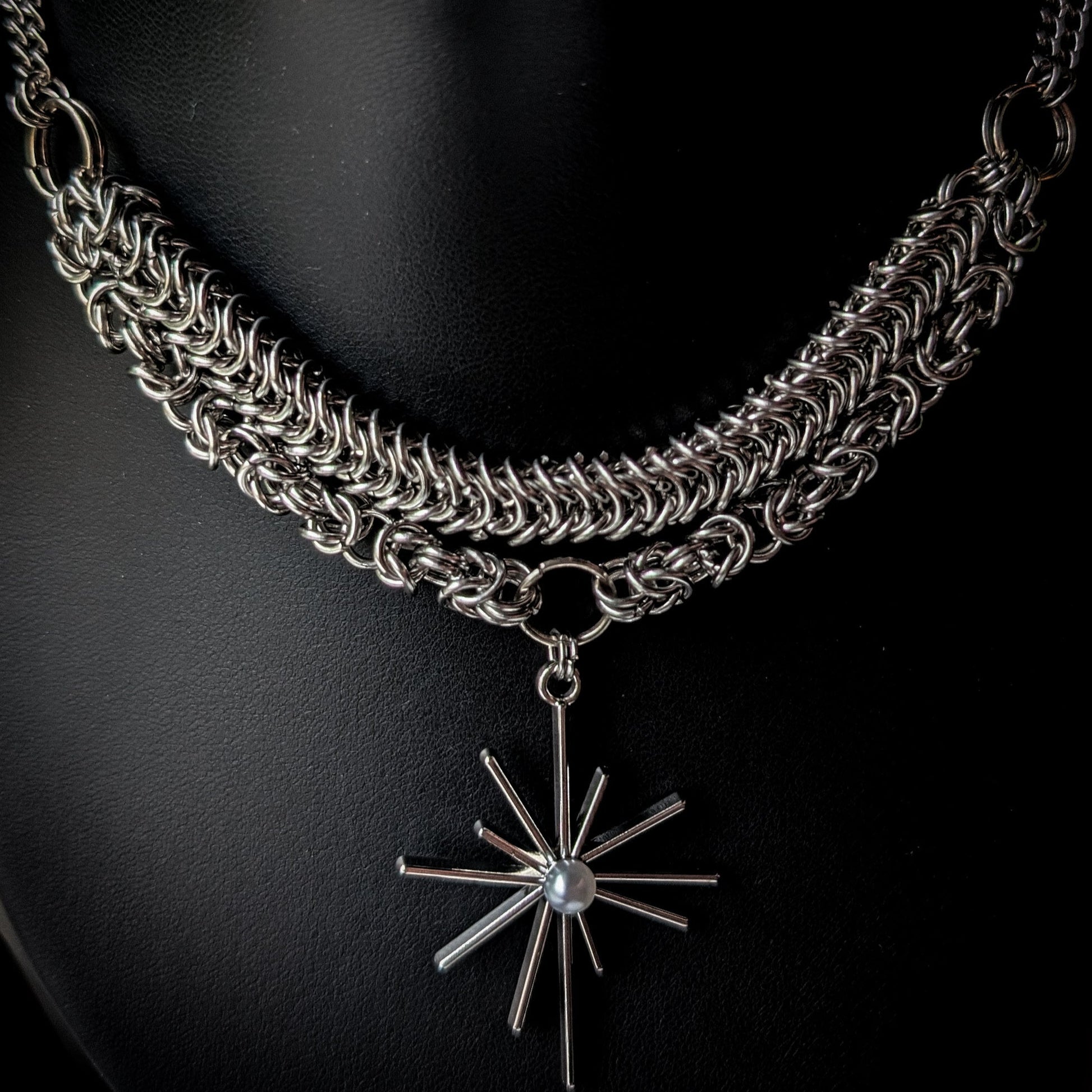 Silver chain necklace with a star-shaped pendant on a black background