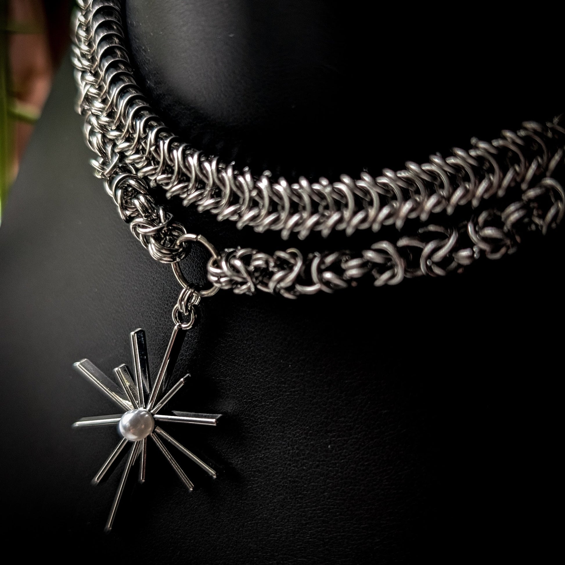 Silver chain necklace with a star-shaped pendant on a dark background